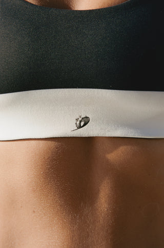 Reversible bikini top with monochrome stripes and solid black finish. Sporty cap sleeve design made from ultra-soft recycled fabric. Volleyball tested for comfort and movement.