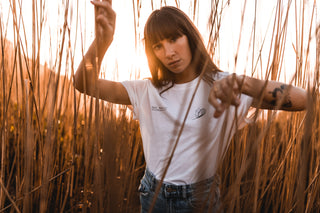 woman wearing a white unisex surf t-shirt by Sea_Washed made from 100% organic cotton at golden hour
